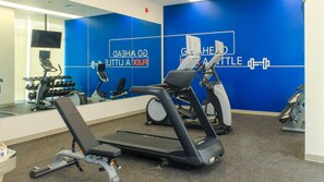 Una palestra con attrezzature per esercizi, uno specchio a parete e una parete blu con scritte.