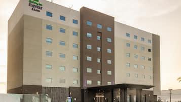 A Holiday Inn Express & Suites hotel with a modern design, featuring a large entrance and multiple floors.