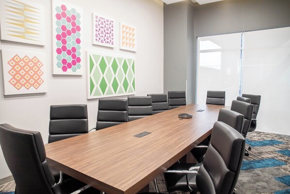 A conference room with a long wooden table, black chairs, and abstract art on the walls.