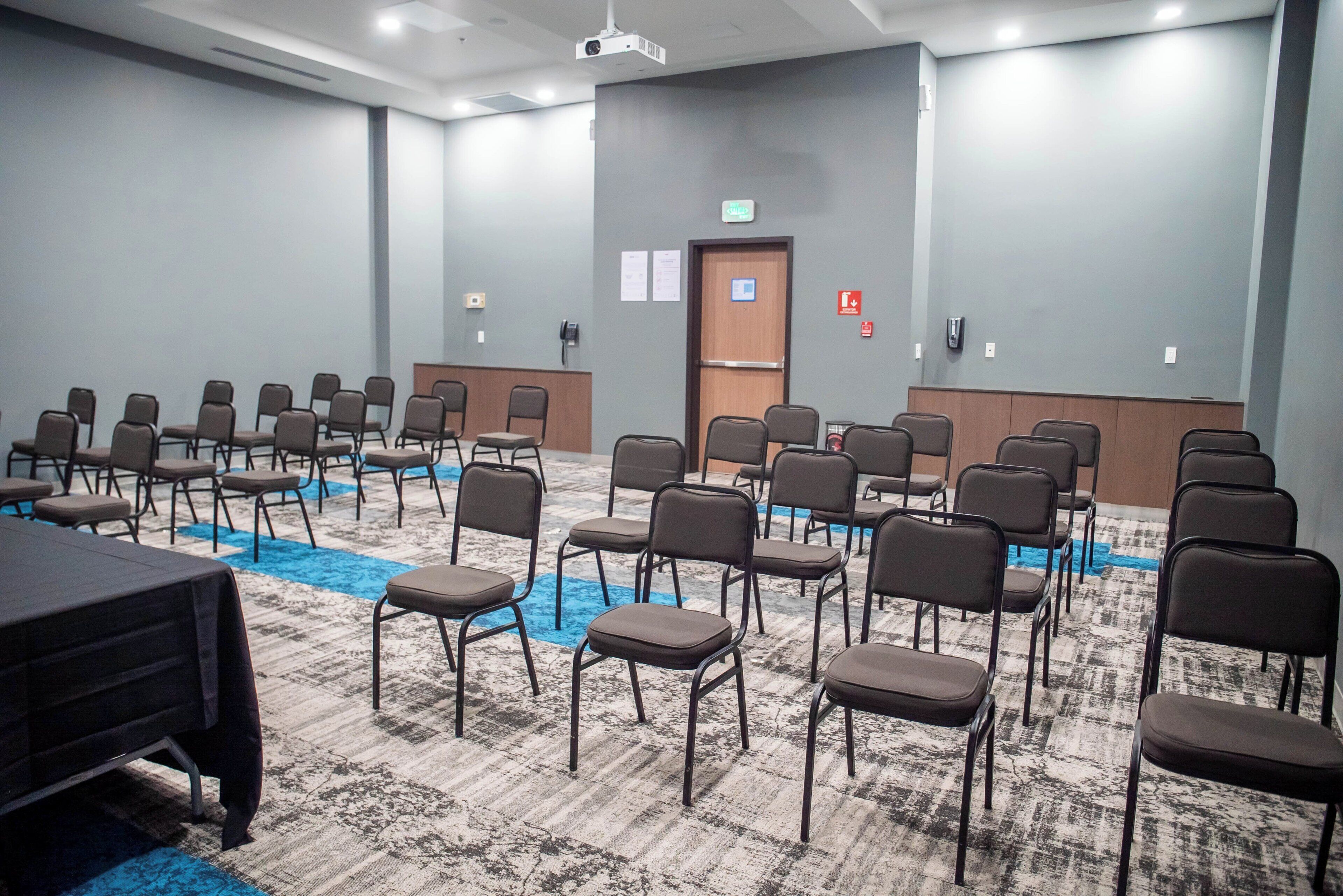 Uma sala de conferências com fileiras de cadeiras, um púlpito e piso coberto de carpete.