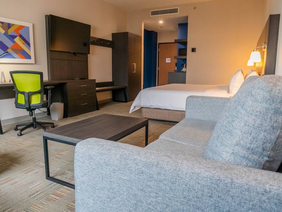 A hotel room with a bed, a sofa, a desk, and a chair.