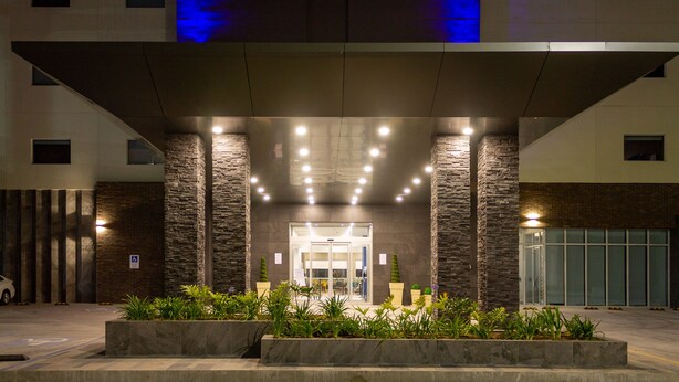 L’entrée d’un hôtel au design moderne, caractérisée par une façade en pierre, un espace d’entrée abrité et un parking.