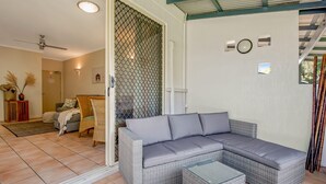 A modern living room with a grey sectional sofa, wicker furniture, and a glass coffee table. - Baden 28 - Rainbow Shores. Top Floor Unit. Air conditioned. Walk to Beach (Rainbow Beach)