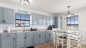 Una cucina moderna con mobili grigi, un'area pranzo con sedie bianche e un tappeto nero.