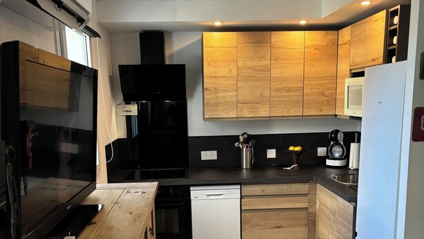 Een moderne keuken met houten kastjes, een vaatwasser, een magnetron en een zwarte oven.