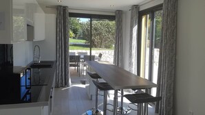 Una cucina moderna con zona pranzo, ampie finestre e vista sull'esterno.
