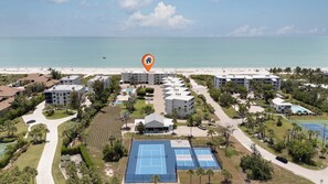 Ett semesterkomplex med flera byggnader, en strand och tennisbanor.