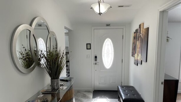 A hallway with a white door, a bench, and a wall-mounted mirror.