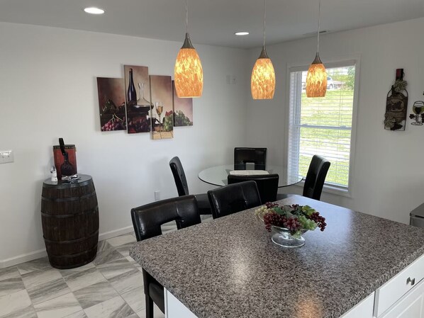 Una cocina moderna con encimeras de granito, sillas negras e iluminación colgante.