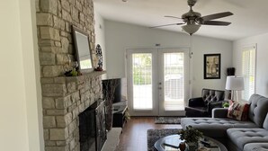 A living room with a stone fireplace, a ceiling fan, a sofa, and a coffee table.