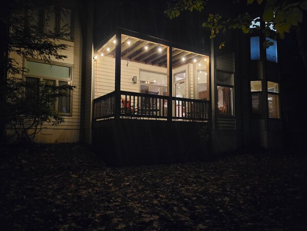 Een huis met een overdekte veranda, een zichtbaar interieur met meubels en een raam met jaloezieën.