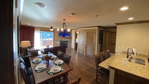 A spacious dining area with a wooden table set for four, a kitchen with granite countertops, and a fireplace.