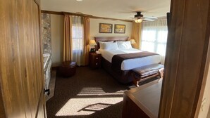 A hotel room with a bed, bedside tables, a ceiling fan, and artwork on the wall.