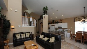 A spacious living area with two black leather sofas, a wooden coffee table, and a dining area with a wooden table and chairs. - Windsor Palms 48 (Kissimmee)