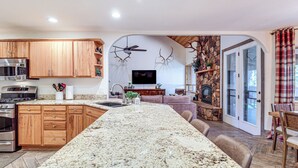 Eine Küche mit Granit-Arbeitsplatten, Holzschränken, einer eingebauten Mikrowelle und einem Kamin aus Stein.