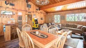 A wooden cabin interior with a dining area, a sofa, and a game table. - PRIME Location~Walk to Ski Shuttle ~ Fully Fenced ~ EV Charger ~ Mini Sled Hill (Big Bear Lake)