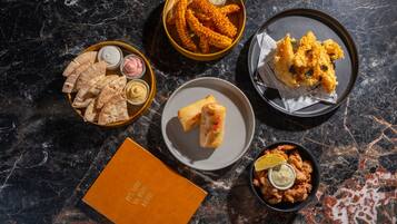 A variety of food items on a marble surface, including fried items and bread.