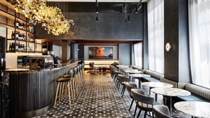 Eine moderne Bar mit einer gebogenen Theke, Sitzgelegenheiten an runden Tischen und einem gemusterten Boden.