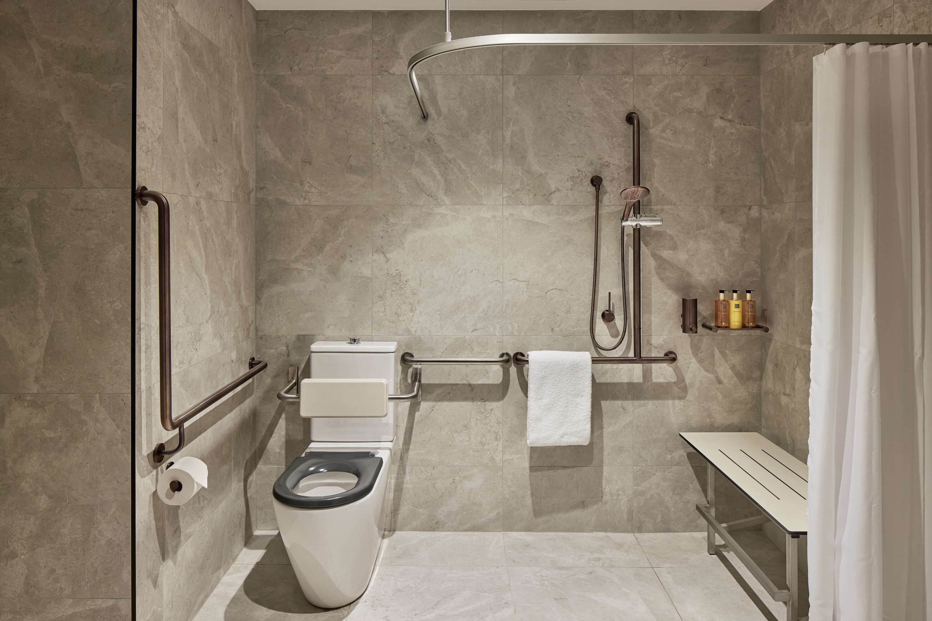 Un baño moderno con inodoro, ducha y un banco.