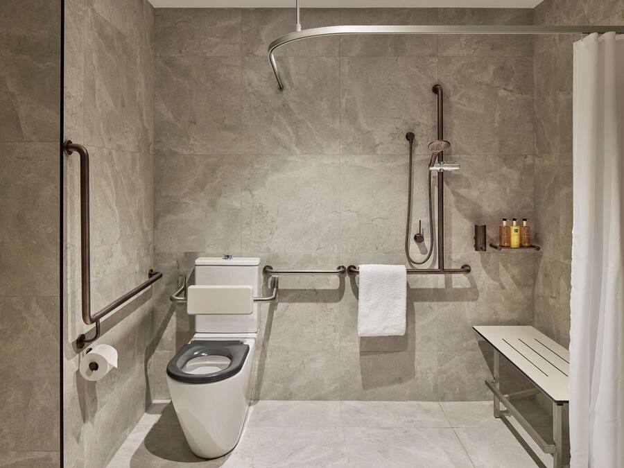 Un baño moderno con inodoro, ducha y un banco.
