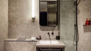A modern bathroom with a large mirror, a sink, a shower, and a towel rack.