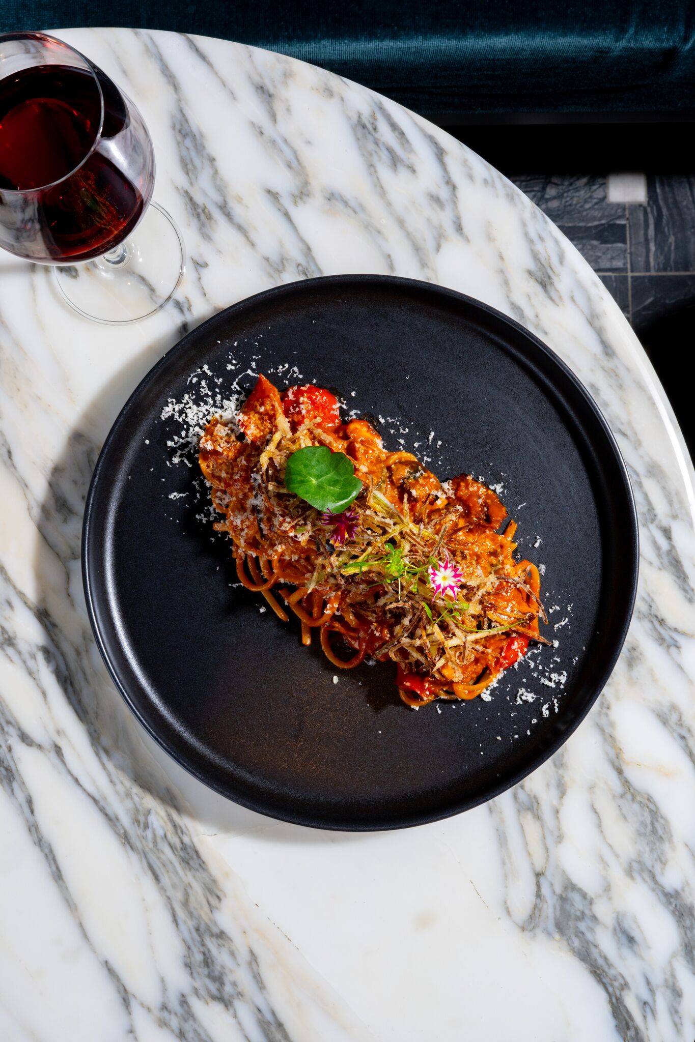 Un plato de pasta sobre una mesa de mármol, con un plato negro.