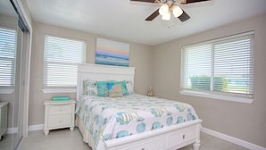 A bedroom with a bed, nightstand, and ceiling fan. - Casa de playa walk to the beach (Ormond Beach)