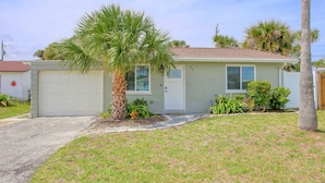 A single-story house with a garage, a palm tree, and a small garden. - Casa de playa walk to the beach (Ormond Beach)