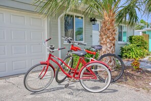 A bicycle is parked in front of a garage with a green door and a small porch area.