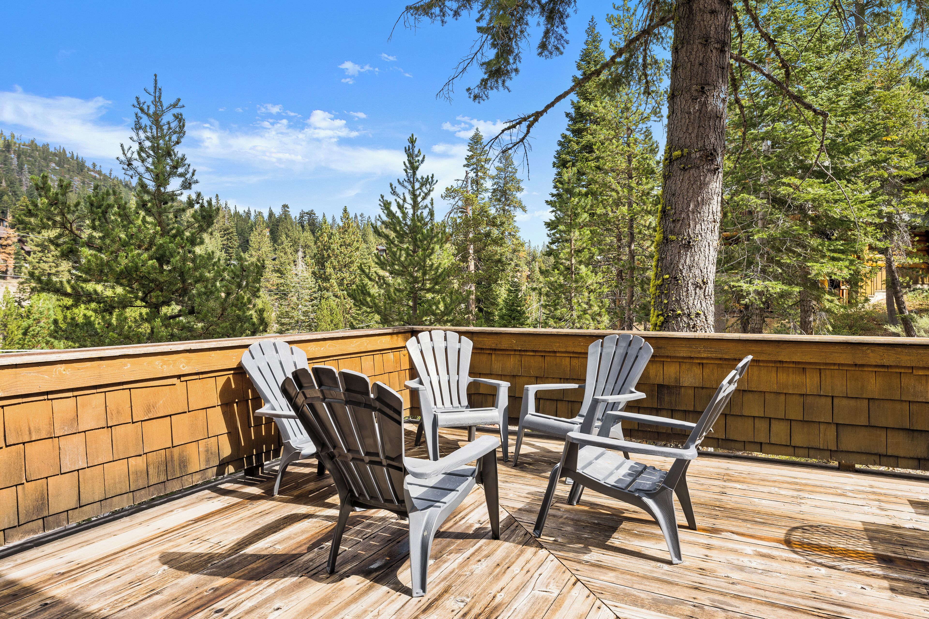 Eine Holzterrasse mit Adirondack-Stühlen und einer Holzverkleidung.
