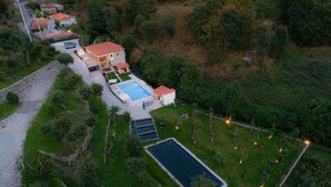 An aerial view of a residential area with houses, a swimming pool, and a tennis court. - Casa Quinta Do Rio (Braga)