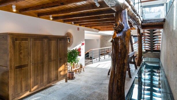 A spacious interior with a high ceiling, wooden beams, a glass staircase, and a view of the outdoors. - Casa Quinta Do Rio (Braga)