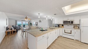 Una cucina moderna con mobili bianchi, un'isola centrale e un'area pranzo con tavolo e sedie.