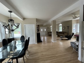 A spacious living area with a dining table, chairs, a sofa, and a ceiling fan.