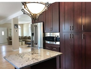 A kitchen with dark wooden cabinets, stainless steel appliances, and a granite countertop.