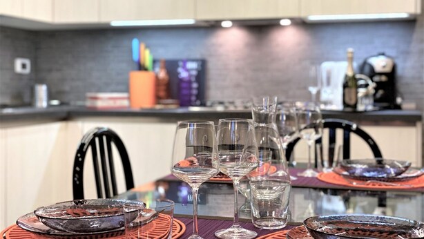 A dining area with a table set for a meal, featuring clear glassware and metal dishes. - LOFT 22 - Moderno a due passi da Piazza del Campo (Siena)