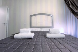 A hotel room with a large bed, two white towels, a headboard with a mirror, and a window with curtains. - LOFT 22 - Moderno a due passi da Piazza del Campo (Siena)