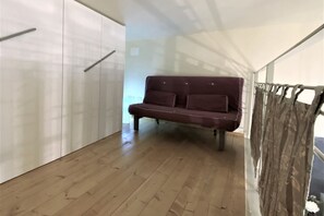 A room with a wooden floor, a dark brown sofa, and white cabinets. - LOFT 22 - Moderno a due passi da Piazza del Campo (Siena)