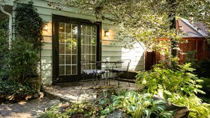 A house with a covered patio, two chairs, and a garden with various plants. - Briar Rose  (Spokane)