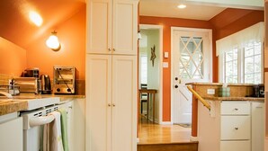 A kitchen with wooden flooring, white cabinetry, and a visible oven. A towel hangs on the oven handle. - Briar Rose  (Spokane)