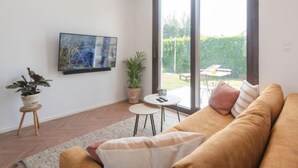 Een moderne woonkamer met een bank, een klein rond tafeltje en een potplant.