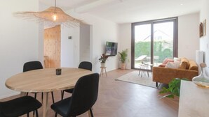 Een moderne woonruimte met een eethoek, een bank en een televisie.