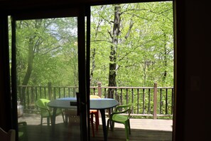 A deck with a table and chairs, surrounded by a wooden railing, overlooking a forested area. - Cozy Retreat in the Poconos Mountains (Bushkill)