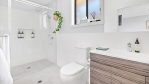 A modern bathroom with a shower, toilet, and vanity.