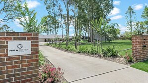 A pathway leading to a building with a sign reading "MALA RETREAT HUNTER VALLEY."