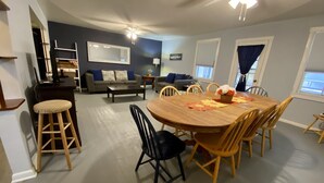 Ein geräumiges Wohnzimmer mit Essbereich, einer Couch, einem Couchtisch und einem Deckenventilator.