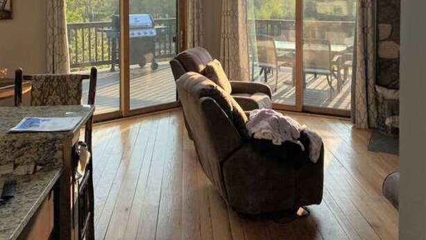 Ein geräumiges Wohnzimmer mit einem großen Schiebeglastür, die auf eine Terrasse im Freien führt.