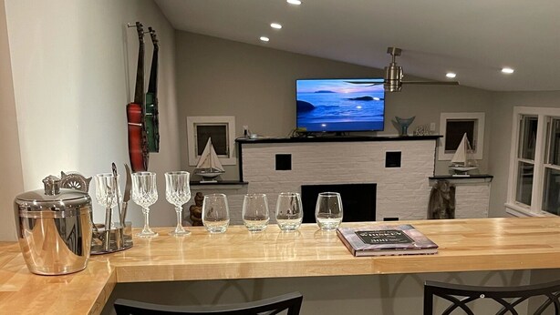 Een moderne keuken met een centraal eiland, barkrukken, een flatscreen televisie en een open haard.