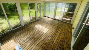 Een overdekt terras met houten vloer, grote glazen deuren en een dakvenster.