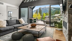 Un salon moderne doté d’une grande porte vitrée donnant sur un balcon, d’une table basse en bois et d’une cheminée en pierre.